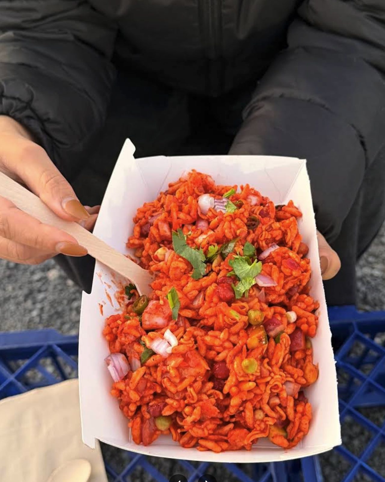 A box of Amilo Piro chatpate being mixed with a wooden spoon, coriander and red onion through it